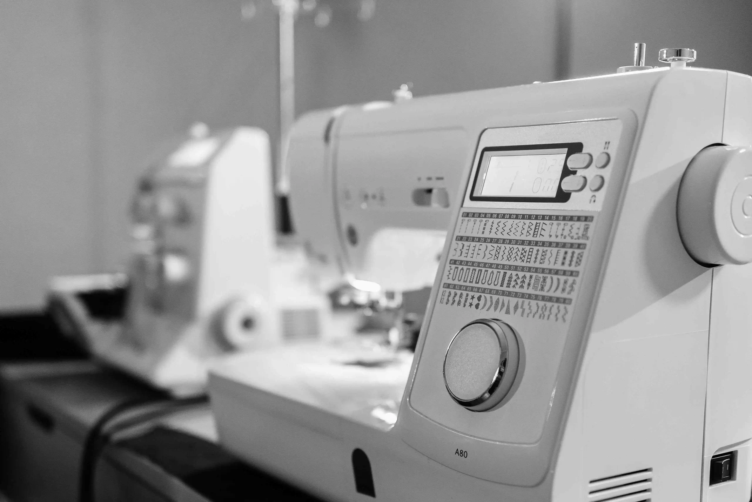 A black and white photo of a sewing machine with variable stitch options, suitable for quilting.