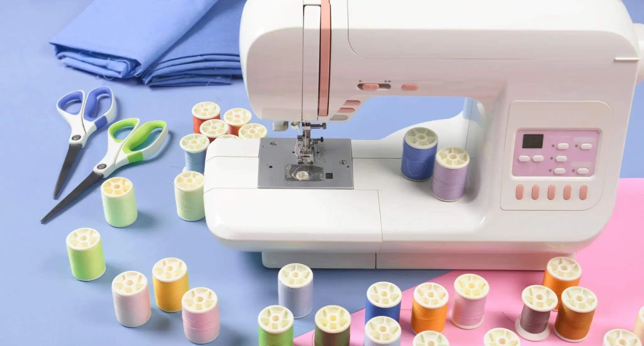 A sewing machine with spools of thread and scissors on a blue background