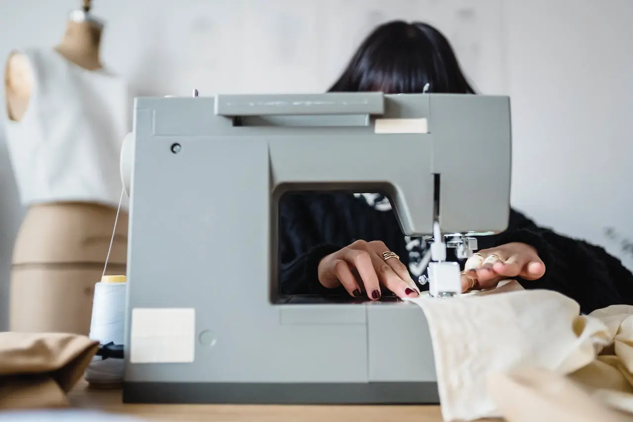 a woman uses a gray sewing machine